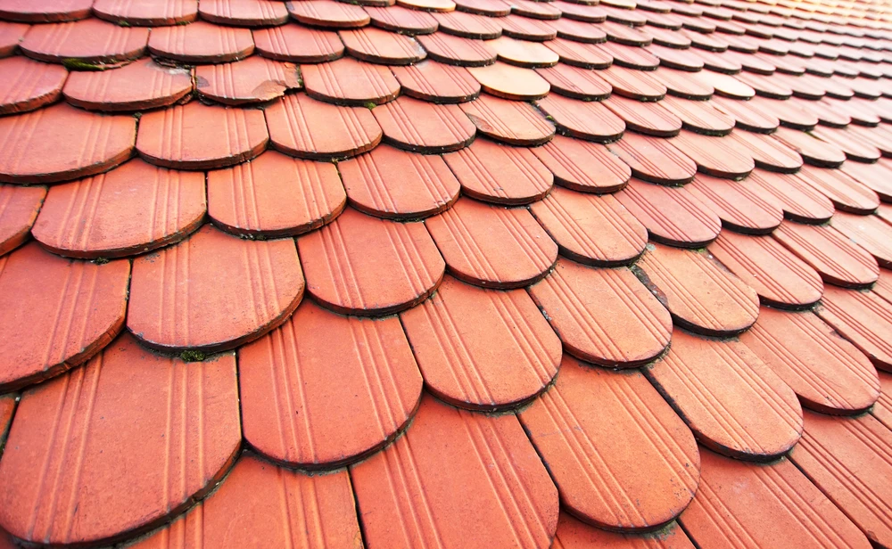 Toiture extérieure avec tuiles en terre cuite rouge-orangé disposées en écailles