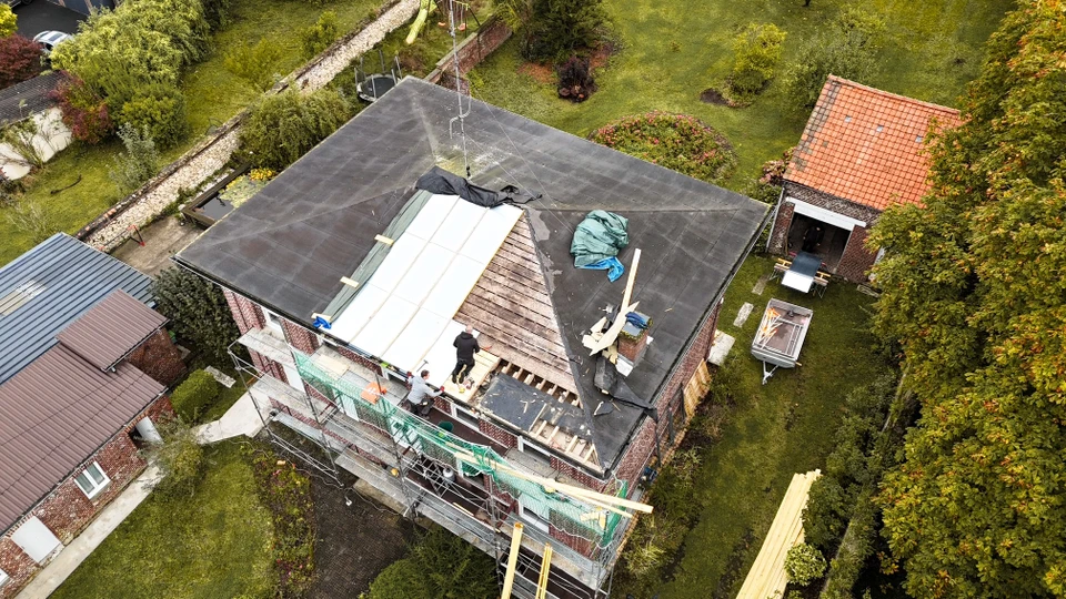 Technicien en combinaison bleue consultant une tablette numérique sur chantier extérieur