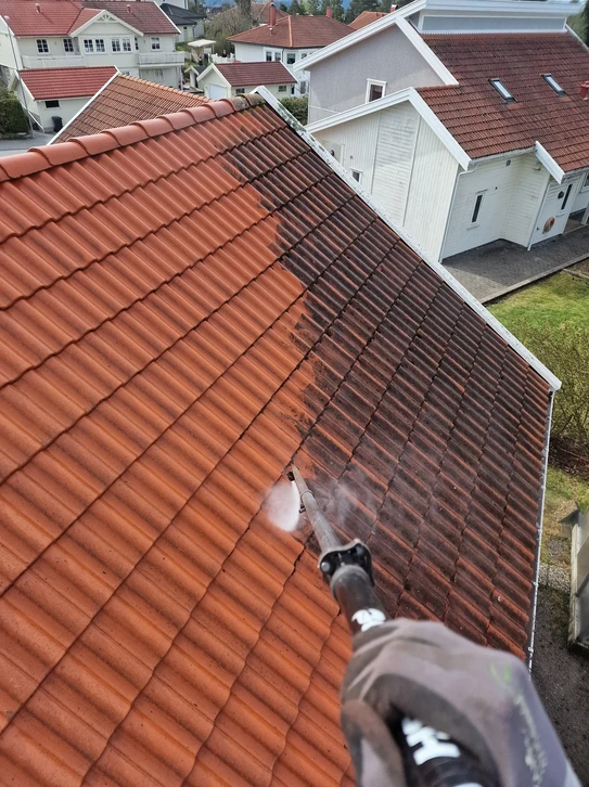 Ouvrier couvreur équipé d'un casque et harnais de sécurité travaille sur toiture métallique grise sous ciel nuagé