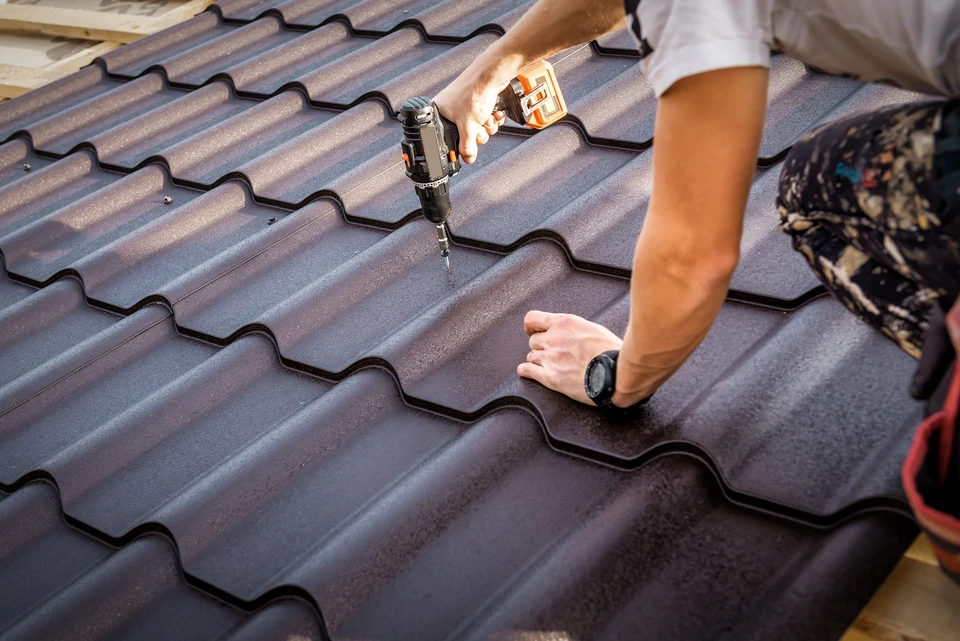 Artisan travaillant sur une toiture en rénovation, utilisant des outils de couverture